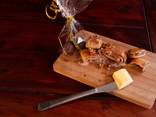 Festive cinnamon rolls with butter and a gift bag of chocolates on a rustic wooden board
