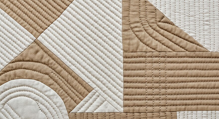 An abstract close-up of a quilted textile featuring beige and white geometric patterns with linear and curved stitching