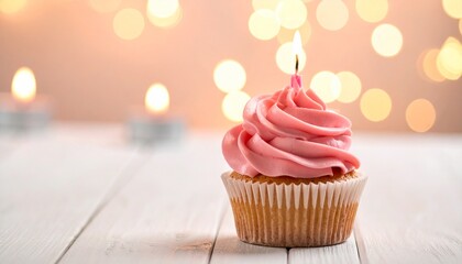 A delicious pink frosted cupcake with a lit candle, perfect for celebrations and birthdays