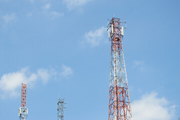 Multiple telecommunication towers with antennas and transmitters rising against a clear blue sky