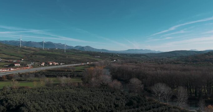 Aerial view of rolling hills, wind turbines, and a bustling highway creates a captivating contrast, Serre, Campania, Italy.