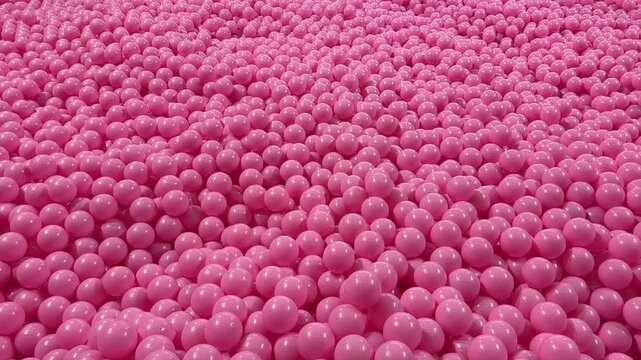 Close up video of many glossy pink spheres packed together creating a smooth abstract texture with playful tone and modern visual atmosphere