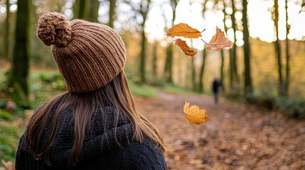 Woman in Knitted Hat Enjoys Autumn Walk with Falling Leaves in Forest
