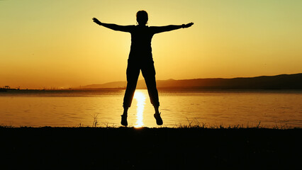 Woman Silhouette With Open Arms At Sunset Beach at Sunset