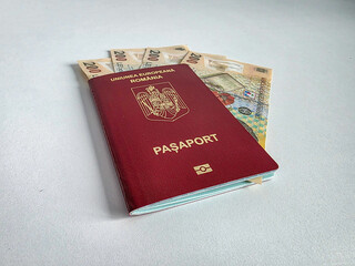 Romanian European Union biometric passport with boarding pass against a white background with Romanian Lei cash money
