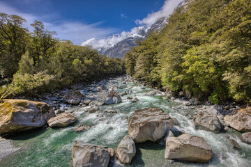 Tutoko River alpine stream with snow-covered mountains at Milford Sound, New Zealand