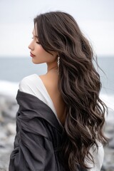 A woman with long brown hair is standing on a beach