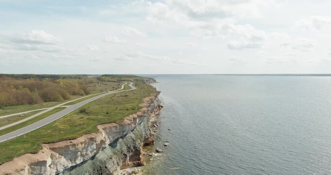Aerial view of Pakri cliff, a dramatic limestone escarpment with a road running along the top of the cliffs in cloudy spring weather, Pakri peninsula, Estonia.