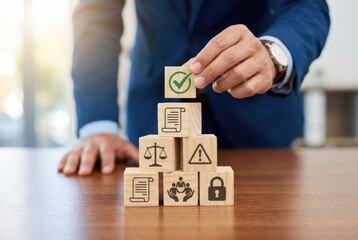 Businessman stacking wooden blocks with icons representing law, safety, and compliance