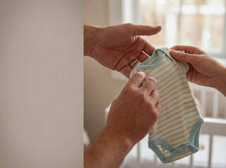 Volunteer hand giving small baby romper clothing donation charity support newborn child care social welfare community service humanitarian aid background copy space hope kindness infant apparel