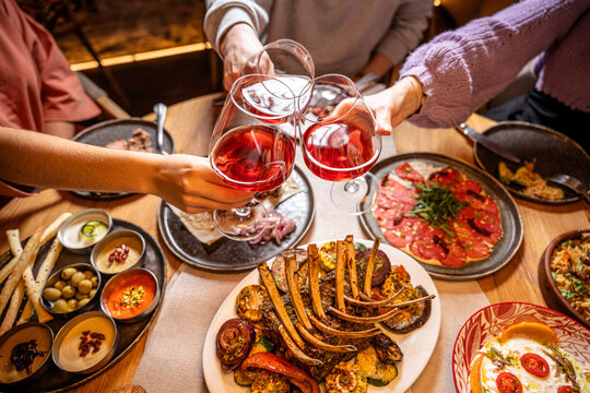Friends clinking wine glasses over shared dinner