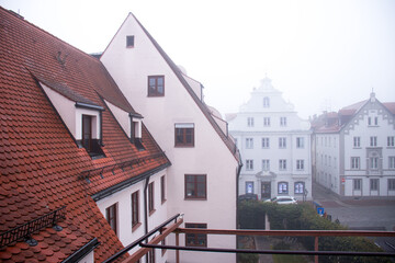 Obraz premium traditional European buildings with red tiled roofs and white facades on a misty morning