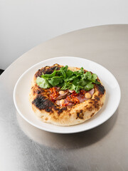 Charred Neapolitan pizza garnished with fresh greens and melted cheese