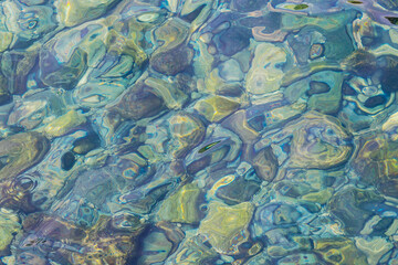 Close-up of clear water splashing over underwater rocks and pebbles.