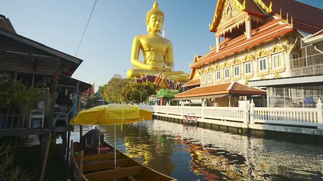 Big Golden Buddha Tep Mongkol Buddha with wooden boat on river at Paknam Bhasicharoen temple or Wat Paknam Bhasicharoen in Bangkok Thailand 