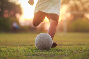Soccer football player with a ball. Action sport outdoors playing football for exercise at green grass field under the twilight sunset.