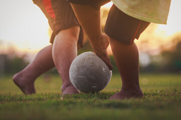 Soccer football player with a ball. Action sport outdoors playing football for exercise at green grass field under the twilight sunset.