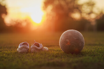 Nostalgic scene of rural childhood sport, soccer football equipment on the ground under warm evening light.