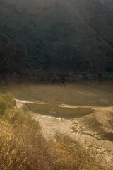 Valley with ancient stone bridge and green vegetation in sunlight. Almogia, Malaga, Andalusia, Spain.