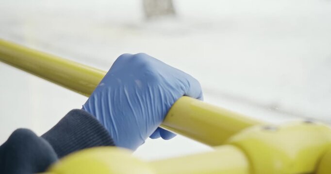 Close up of passenger on bus protecting from global pandemic. Hand in medical glove holding yellow pipe, preventing covid-19 outbreak. Concept of modern quarantine measures. 