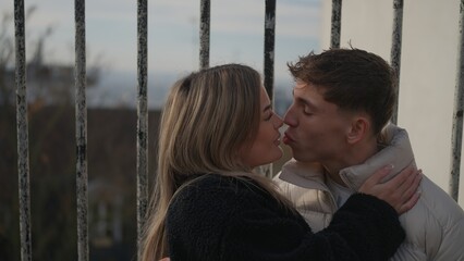 Obraz premium A young couple kisses affectionately in Paris France with a cityscape in the background. This image can be used to illustrate themes of love travel and romantic getaways.