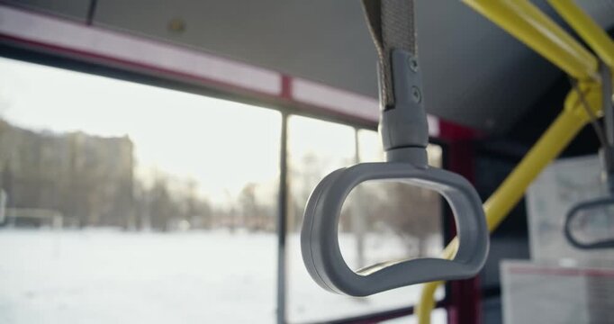 Close up of grey bus hadle, bus stopping. Handle usrd for passenger holding, keeping balance, city on background, blurred, house, trees, park. Concept of public transport,