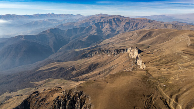 Vast mountainous landscape with rugged terrain and distant peaks under clear blue sky - Powered by Adobe
