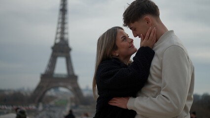 A romantic couple embraces in Paris France with the Eiffel Tower in the background expressing love and tenderness. This image is suitable for travel tourism and relationship concepts.