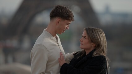 A young romantic couple embraces in Paris France with the Eiffel Tower in the background. This image is perfect for illustrating themes of love travel and European city breaks. © 4kclips