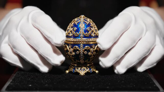 Hands in White Gloves Placing Jeweled Faberge Egg on Black Velvet Stand Cinematic