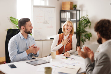 Three business team members share ideas during a brainstorming session at a bright office. They show enthusiasm and collaboration as they plan for success.