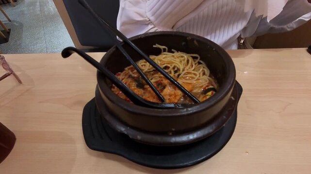 Videography of a woman's hands pinching and slurping ramen noodles with chopsticks. Footage of a woman enjoying spicy ramen with chopsticks. Food Footage in 4K HD Resolution