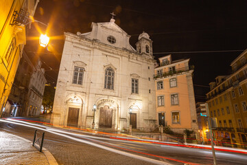 Fototapeta premium Night Street Scene With Historic Church Facade And Warm Streetlight Glow In Urban Nightlife lisbon Portugal