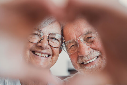 Senior couple, hands and heart symbol in retirement home with smile for care, love and support. People, relationship and happy as pensioner for marriage, trust and commitment or romance as soulmates