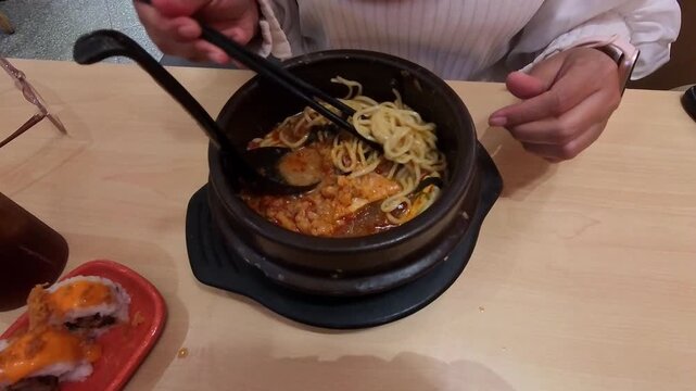 Videography of a woman's hands pinching and slurping ramen noodles with chopsticks. Footage of a woman enjoying spicy ramen with chopsticks. Food Footage in 4K HD Resolution