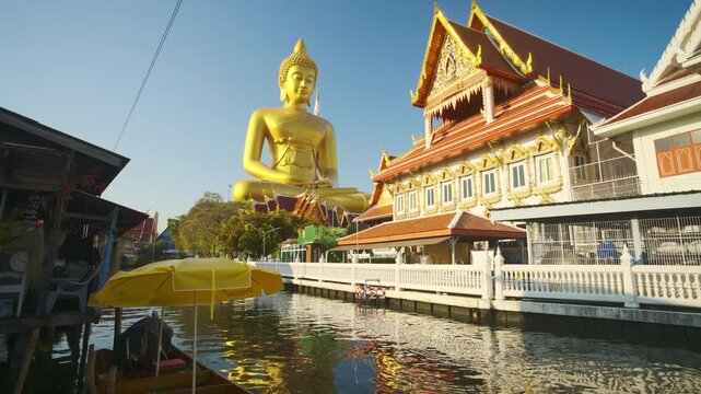Big Golden Buddha Tep Mongkol Buddha with wooden boat on river at Paknam Bhasicharoen temple or Wat Paknam Bhasicharoen in Bangkok Thailand 