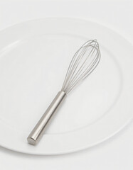 High‑resolution studio image of a brushed‑aluminum kitchen whisk, its metallic sheen catching a soft white key‑light, placed on a spotless white plate.