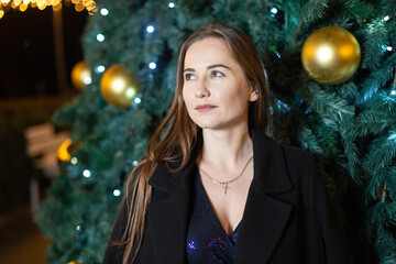 Happy young woman against the backdrop of festive Christmas lights