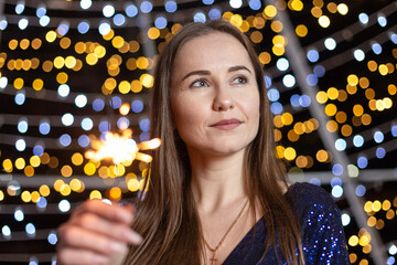 Happy young woman against the backdrop of festive Christmas lights