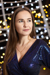 Happy young woman against the backdrop of festive Christmas lights