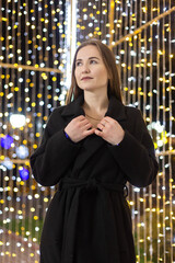 Happy young woman against the backdrop of festive Christmas lights