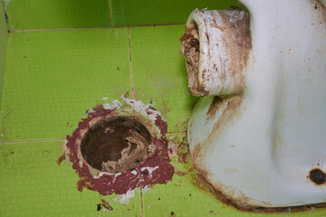 open dirty sewer hole near toilet, old toilet with clogged sewer hole in floor