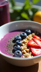 Healthy berry smoothie bowl topped with fresh blueberries, strawberries, chia seeds and granola.