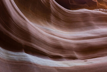 Waves of color and texture in a narrow canyon formed by erosion. Abstract textured earth tones background.