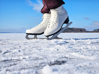 Close-up of a white ice skate gliding over a frozen lake, showcasing the blade's sharp edge and the sparkling snow, capturing the essence of winter sports and outdoor activities