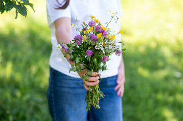 Close up of woman in blue jeans holding a bouquet of beautiful wildflowers