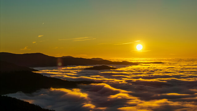 Sonnenaufgang &uuml;ber den Wolken, mit Bergen im Hintergrund, gesehen von einem Aussichtspunkt in den fr&uuml;hen Morgenstunden