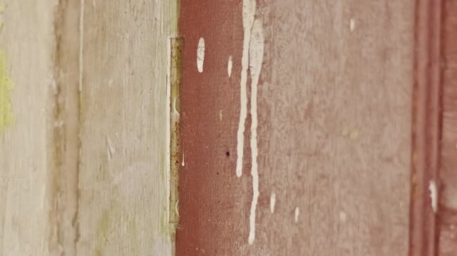 Old rusty metal door hinge on a brown wooden frame being moved slowly while the door opens and closesc