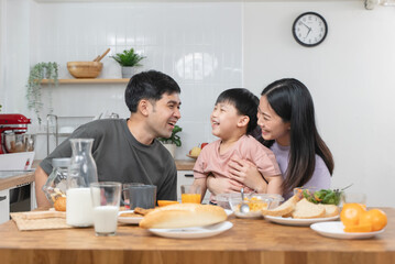 happy family together. Asian parent eating breakfast with little son in the kitchen.