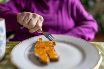 Senor woman eating bread with jelly in a home setting